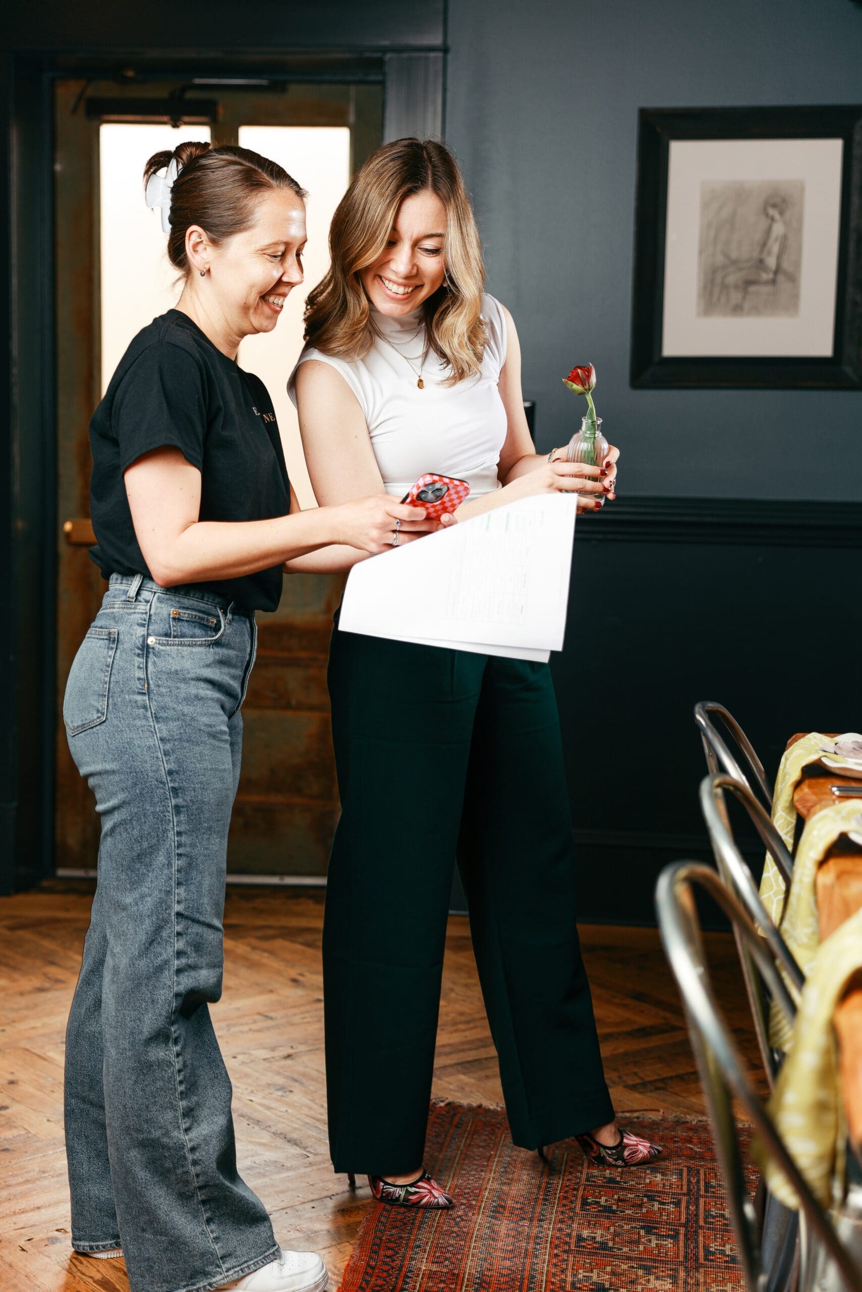 two women discuss wedding planning spreadsheets by a set table