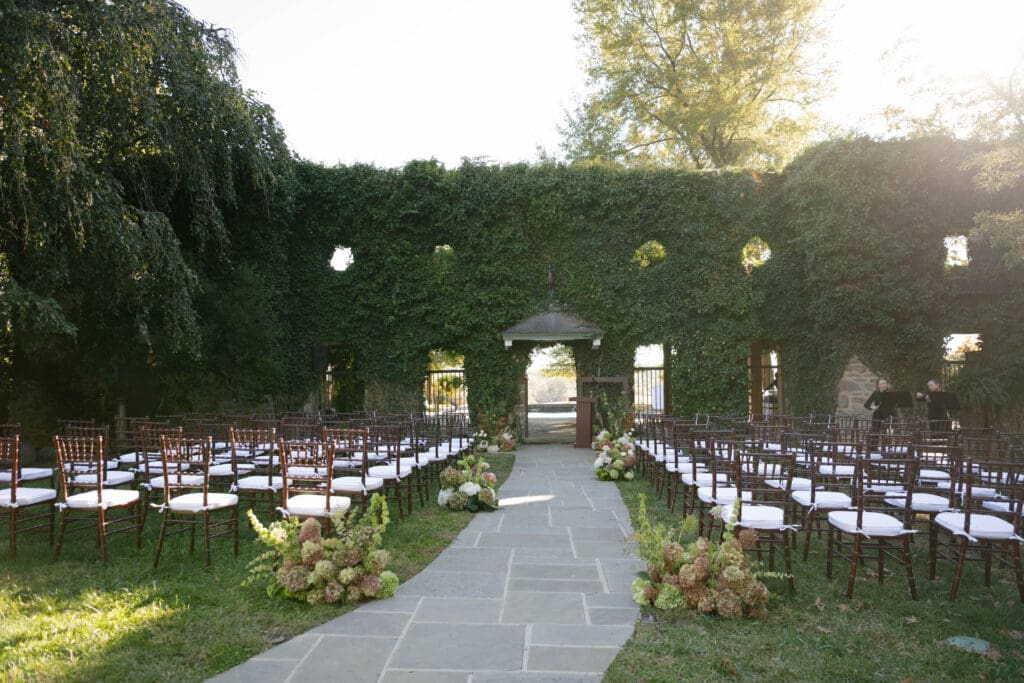 Ivy wall with ceremony chairs and floral arrangements in front